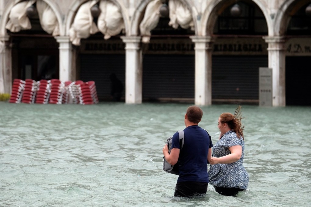 A couple walk in the flooded Saint Mark Square during flooding in Venice on Monday. Photo: Reuters