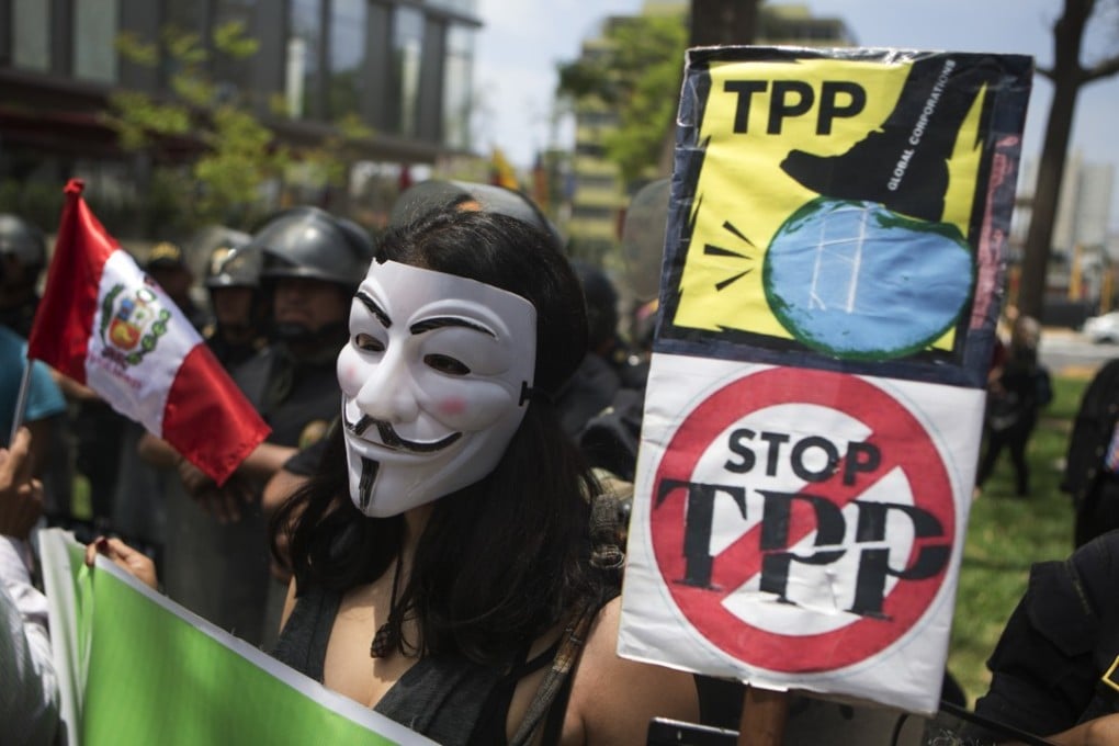A protester holds signs against the TPP during a rally in Lima, Peru. Photo: AP