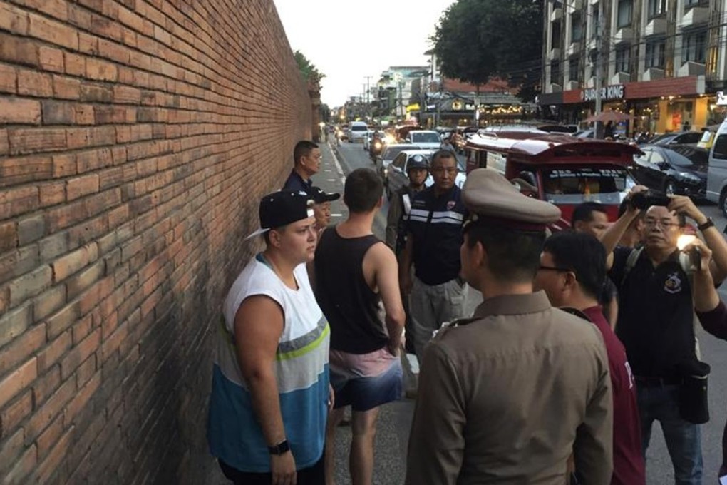 Tourists Lee Furlong (in black) and Brittney Schneider (in white) stand in front of Tha Pae Gate, in Chiang Mai, Thailand, on October 18. They face up to 10 years in prison on charges of spraying painting the ancient brick wall. Picture: AP