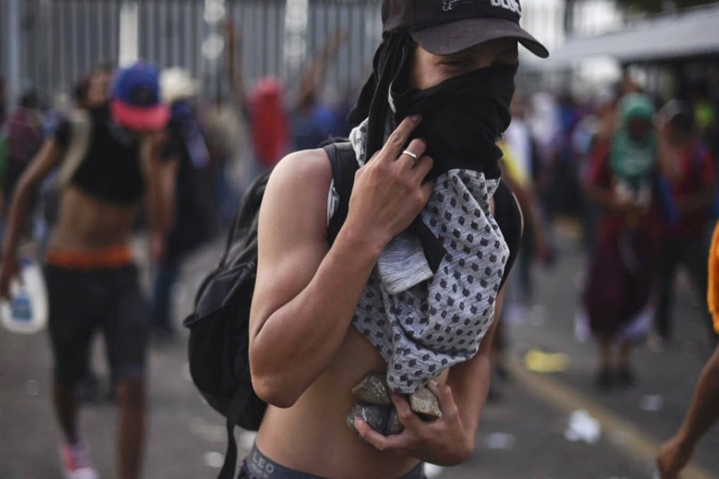 A Honduran migrant taking part in a caravan heading to the US, is pictured holding stones in the border between Ciudad Tecun Uman in Guatemala and Ciudad Hidalgo, Mexico. Photo: AFP
