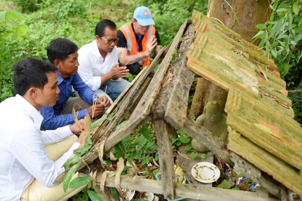David MacMillan, an expert from SparrowHawk Far East company, prays with teachers before a search for mass graves at a school compound in Prey Veng province, Cambodia. Photo: AFP