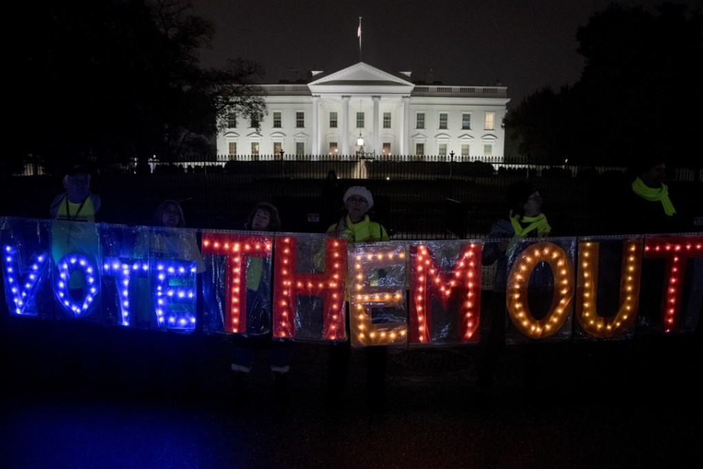 A group of people hold up a sign that reads ‘Vote Them Out’ as they protest in front of the White House the night before the midterm elections. Photo: AP