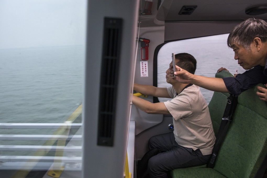 Passengers take photographs while crossing the Hong Kong-Zhuhai-Macau Bridge towards Hong Kong on October 24. The bridge comes with a hefty price tag, but the economic and other benefits will be enjoyed by generations to come. Photo: Bloomberg
