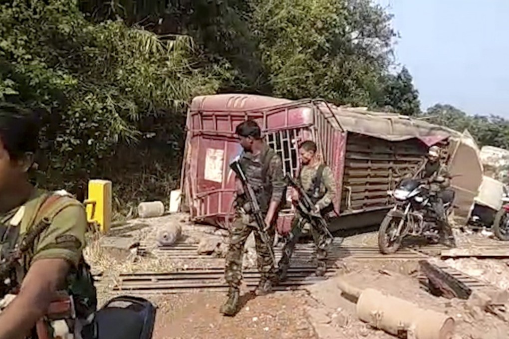 Indian paramilitary soldiers walk past the remains of the bus. Photo: KK Production via AP