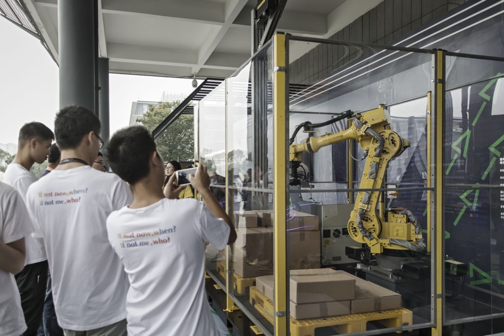 Employees and visitors take photographs of logistic and parcel delivery robots on display at the Alibaba Group Holding Ltd. headquarters in Hangzhou, China, on Friday, Sept. 8, 2017. Photo: Bloomberg