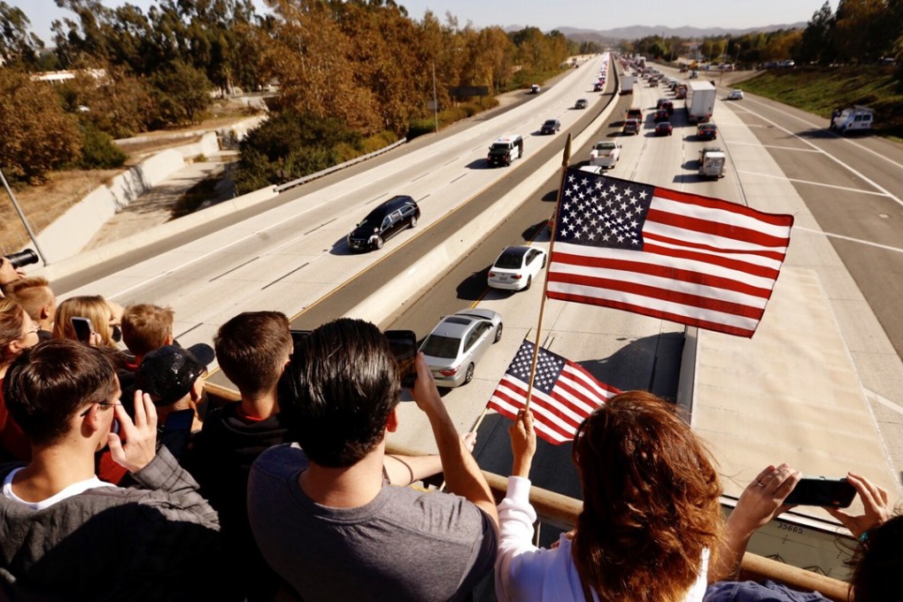 Mourners watch the procession as the hearse carrying the casket of Ventura County Sheriff’s Sergeant Ron Helus passes them on Thursday in California. Photo: TNS