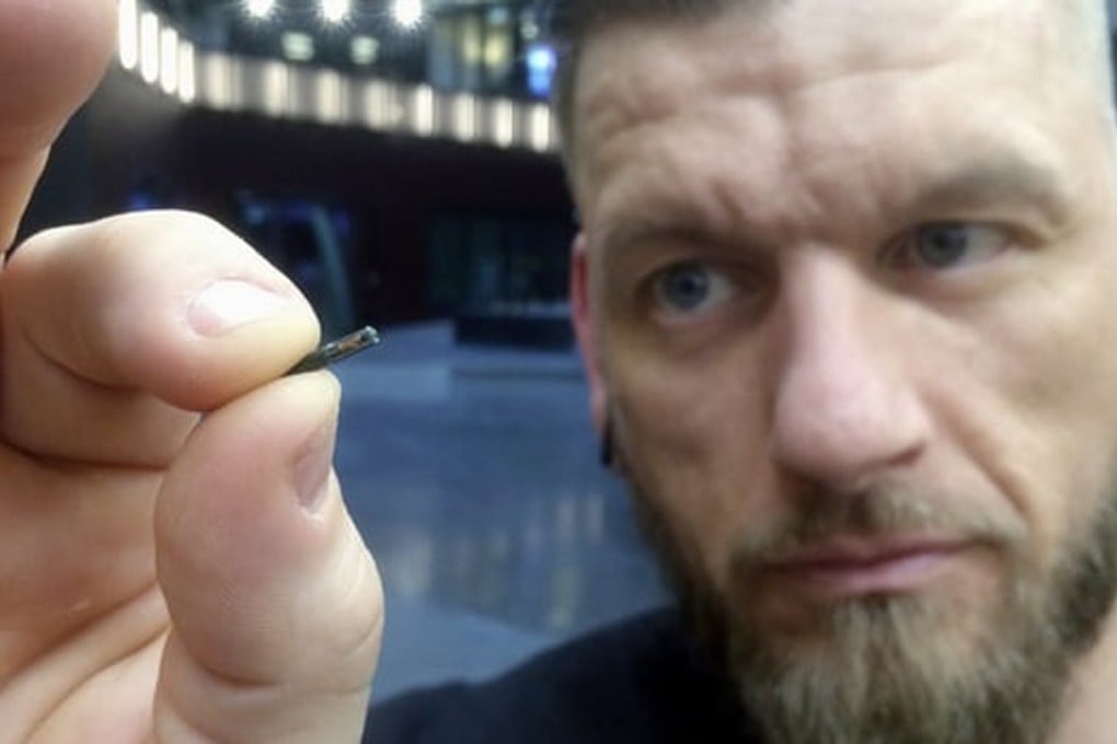 Jowan Österlund from Biohax holds a microchip implant the size of a grain of rice between his thumb and forefinger. Photo: AP=