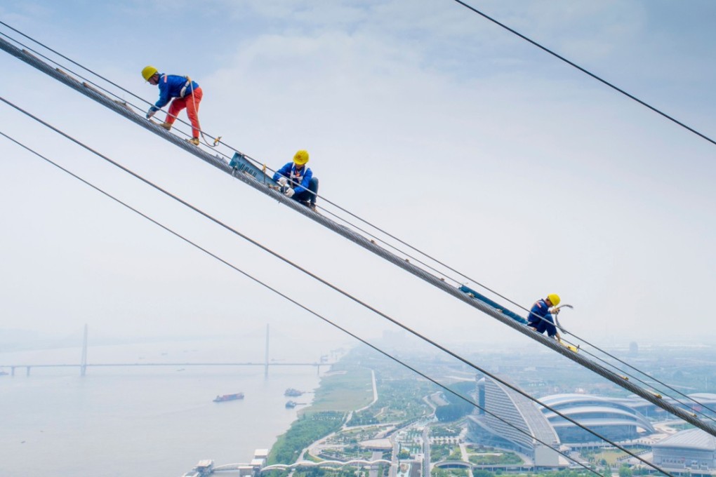 Workers build a suspension bridge over the Yangtze River in Wuhan. China needs to spend more, including on infrastructure, to arrest the economic slowdown. Photo: AFP