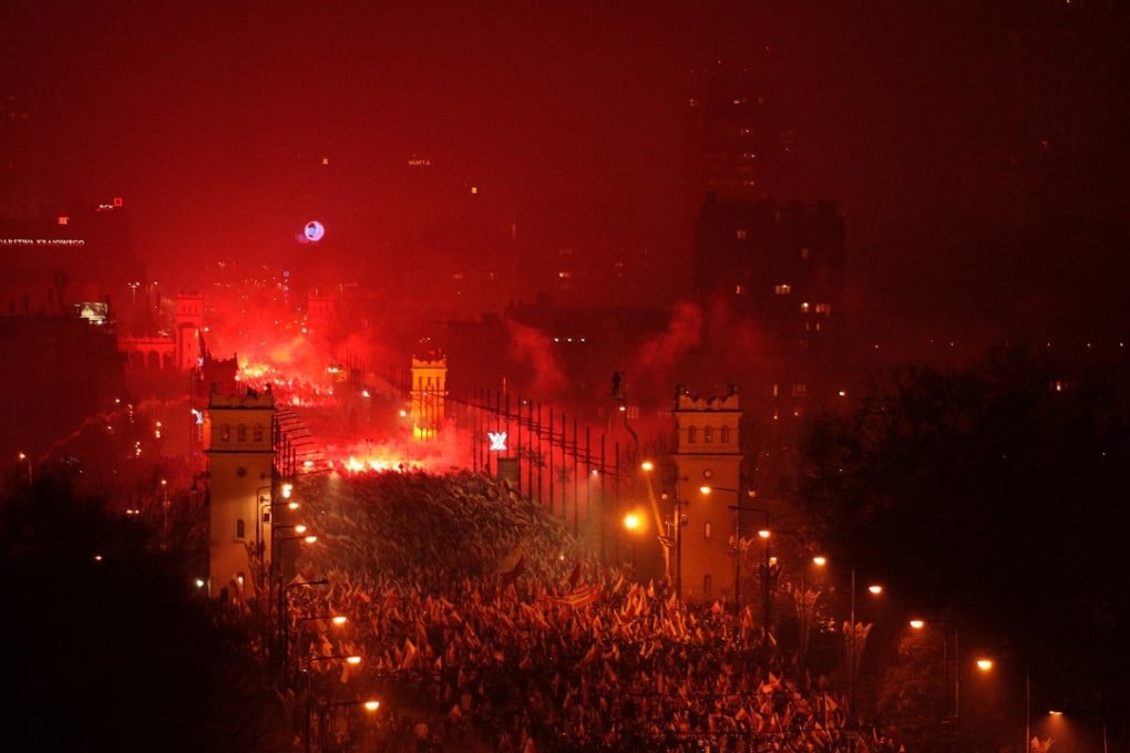 People carry Polish flags and burn flares as they walk past the Poniatowski Bridge during a march marking the 100th anniversary of Polish independence in Warsaw. Photo: Reuters