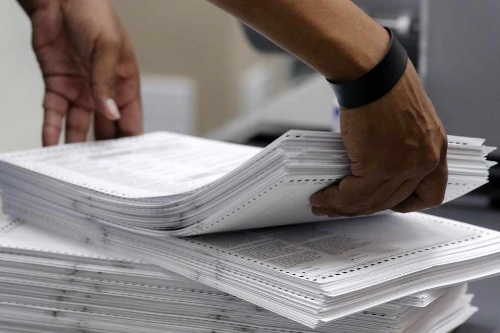 Elections staff load ballots into machine as recounting is underway at the Broward County Supervisor of Elections Office. Photo: AFP