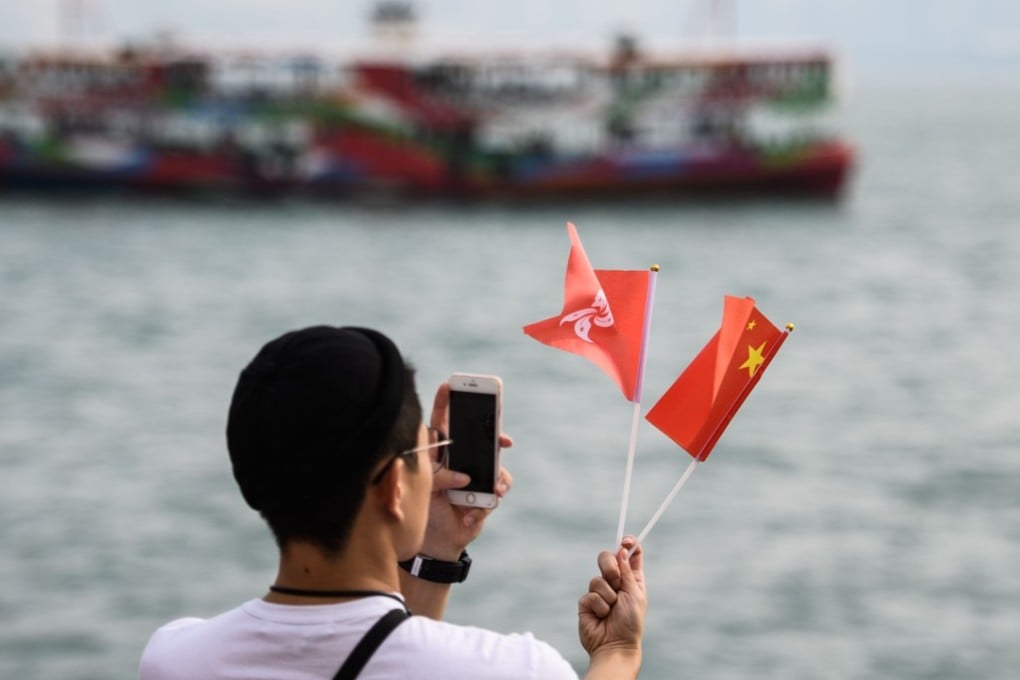 A man takes a photo of the Hong Kong and Chinese flags as a Star Ferry sails past after a flag-raising ceremony as part of China’s National Day celebrations in Hong Kong on October 1. Photo: AFP