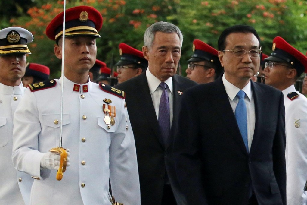 Chinese Premier Li Keqiang, center right, inspects an honour guard with Singaporean Prime Minister Lee Hsien Loong during a visit at the Istana in Singapore on Monday. Photo: Reuters