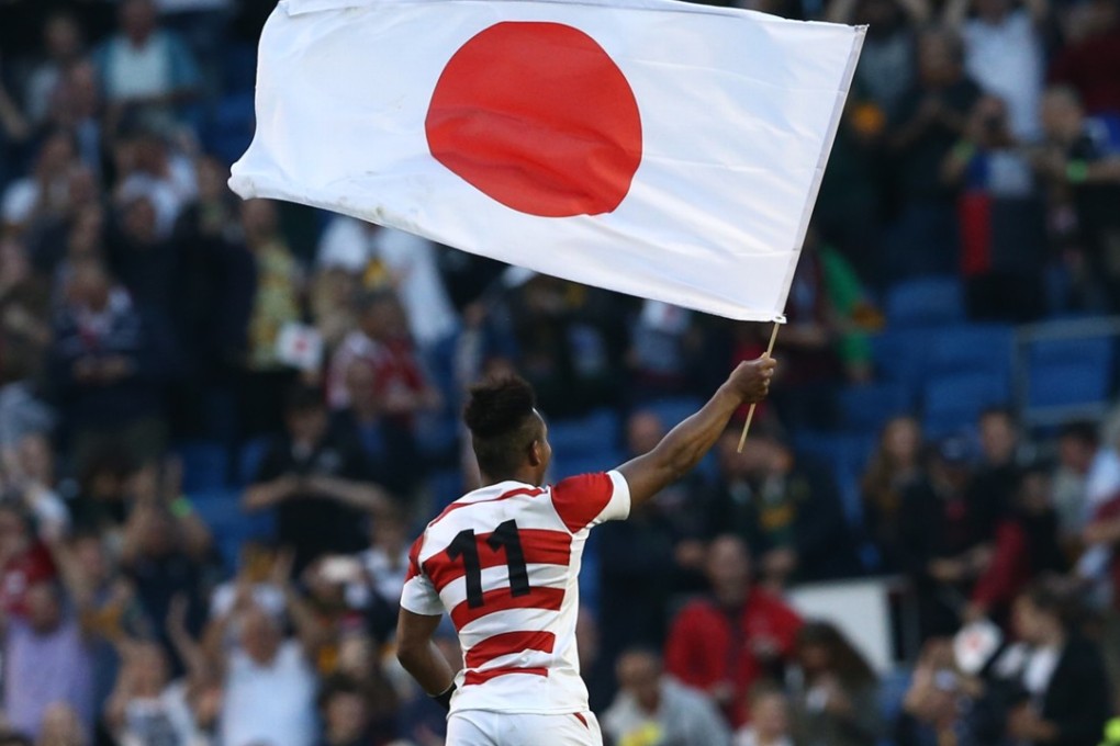 Japan's wing Kotaro Matsushima waves the Japanese national flag as the team celebrate their victory over South Africa in the 2015 Rugby World Cup. Photo: AFP