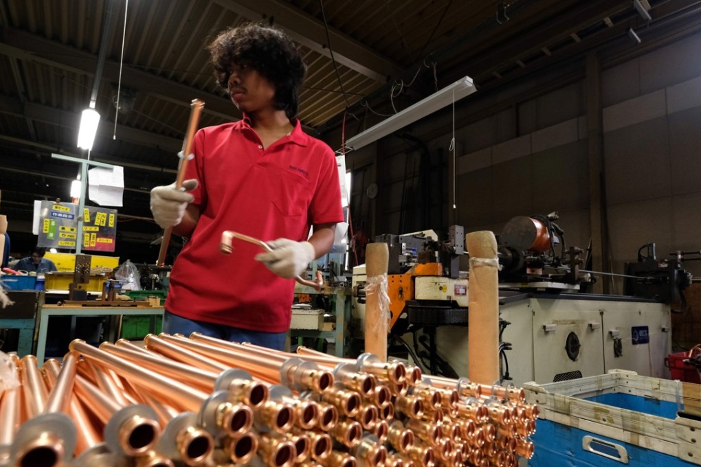 An Indonesian worker processes copper pipes at a factory in Oizumi, Japan. Photo: AFP
