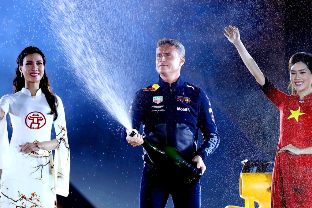 Former Formula One driver David Coulthard (centre) is flanked by Vietnamese models wearing traditional dresses during a ceremony in Hanoi. Photo: EPA