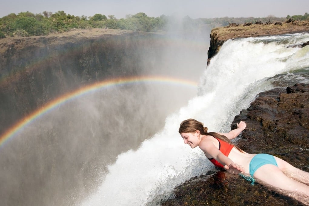 A tourist leans over the edge of Devil’s Pool, at the top of Victoria Falls. Pictures: Alamy