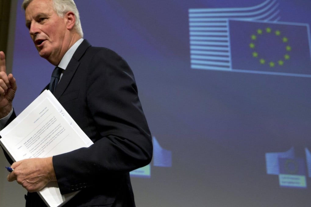 EU chief Brexit negotiator Michel Barnier holds a copy of the 585-page draft withdrawal agreement during a media conference in Brussels on Wednesday. Photo: AP