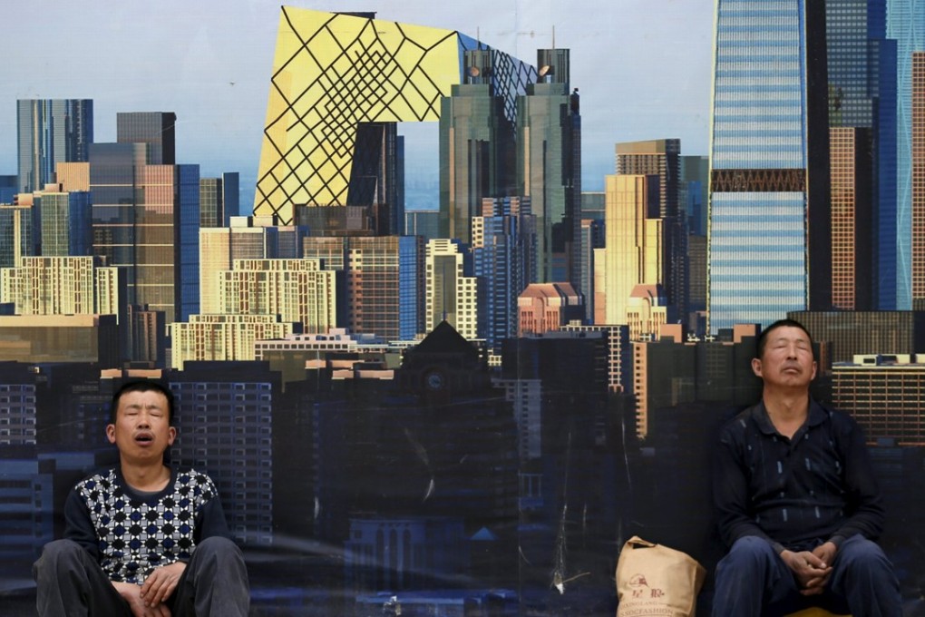 Construction workers nap in front of a wall with a poster of the city’s skyline at a construction site in Beijing, in May 2015. China’s property bubble has begun to unwind, hitting the economy hard. Photo: Reuters