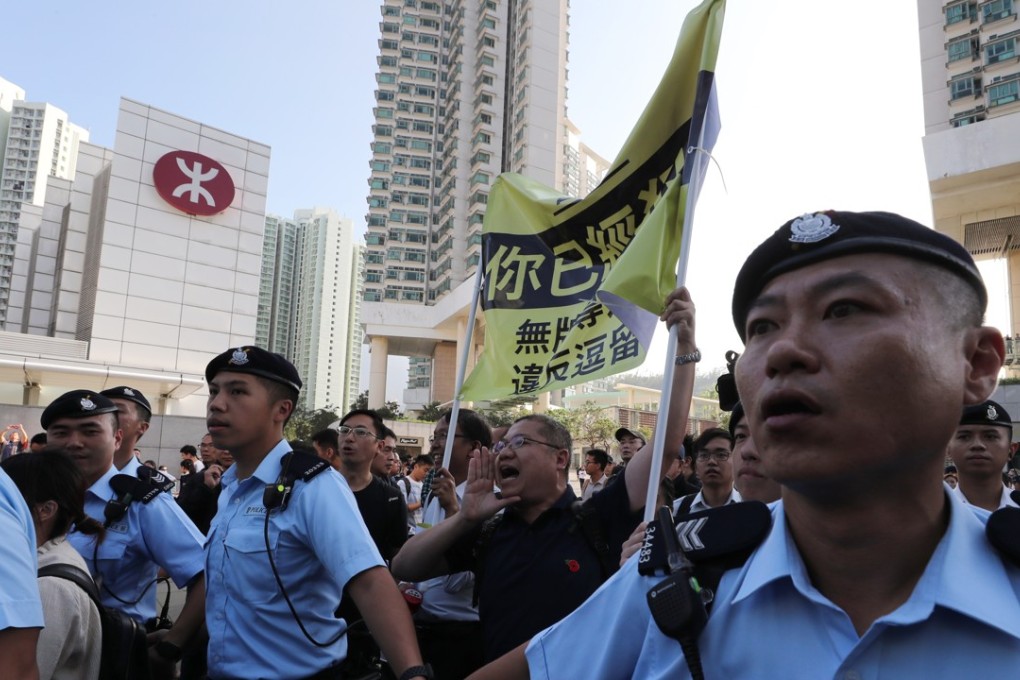 Police officers stand by while protesters shout slogans during a rally against illegal tour guides that have been blamed for worsening the problem of overcrowding in Tung Chung. Photo: Sam Tsang