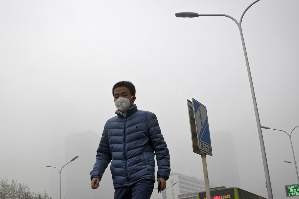 A man wearing a mask walks through the central business district of Beijing blanketed by heavy smog last Wednesday. Photo: AP