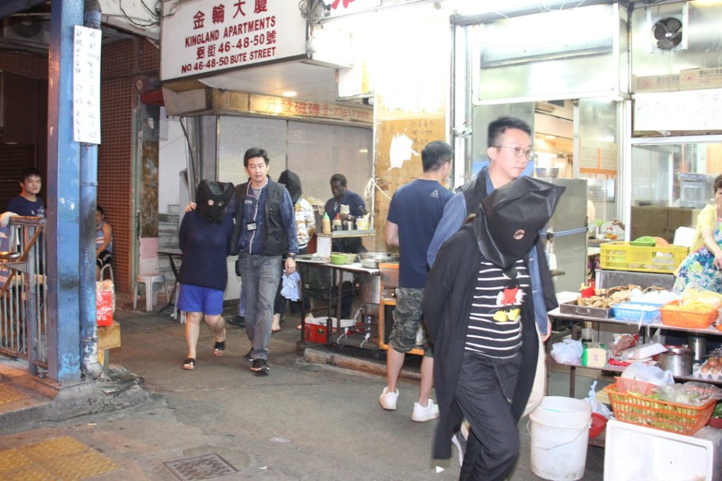 At about midnight, the trio, who were hooded and handcuffed, were escorted to a flat in Kingland Apartments on Nathan Road, Mong Kok for a search. Photo: Handout