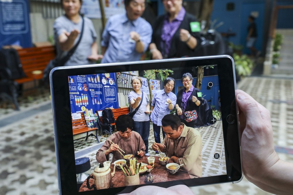 Japanese artist Masaki Fujihata is flanked by two Wan Chai residents as they try out his augmented reality project. Photo: Dickson Lee