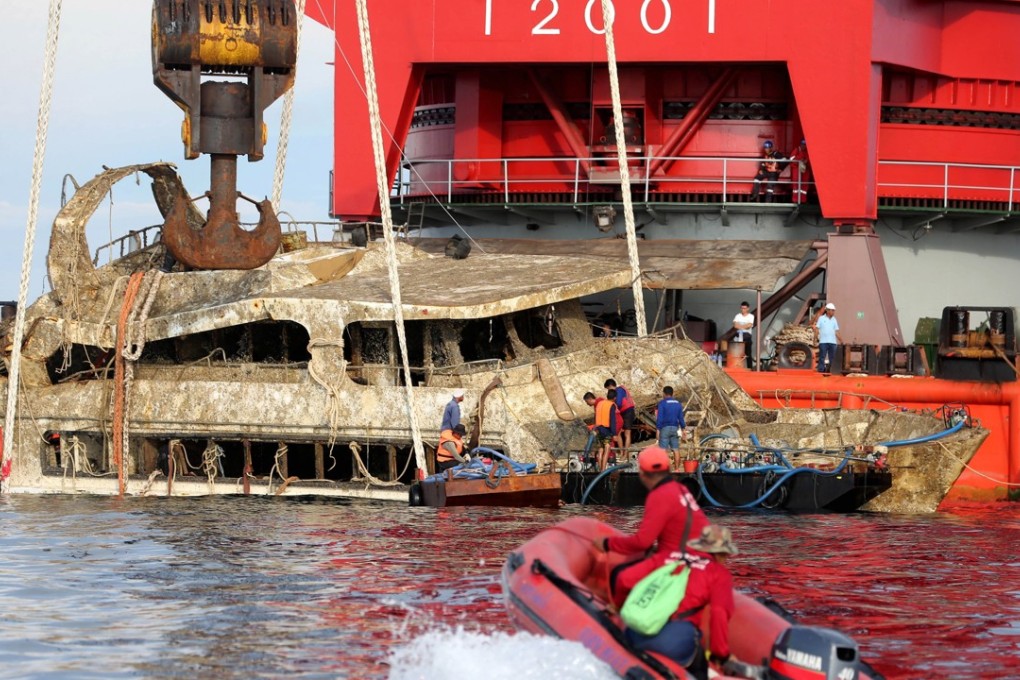 Thai officers use a crane to retrieve the tour boat that capsized in the sea near Phuket island. Photo: EPA