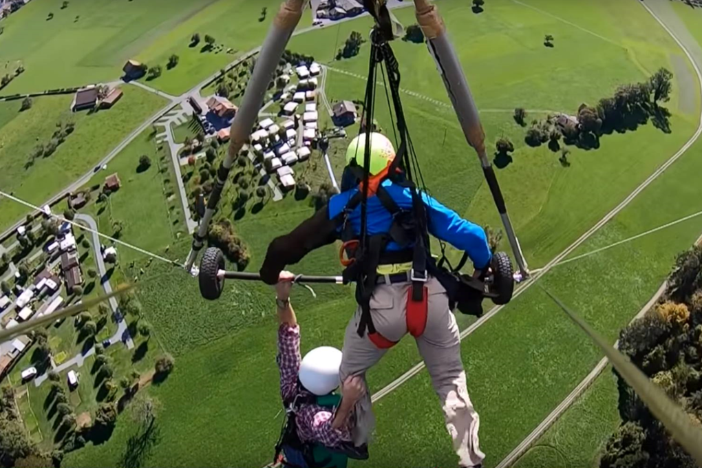 Florida man Chris Gursky (left) clings to his hang-gliding pilot in a video of his wild ride in Switzerland. Photo: Chris Gursky / YouTube