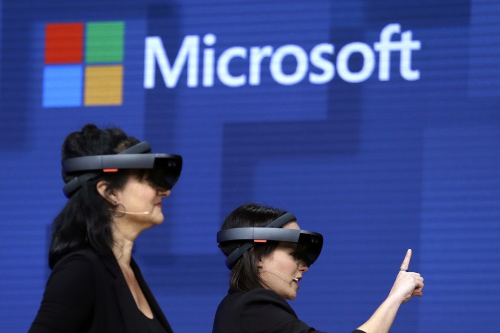 FILE- In this May 11, 2017, file photo, members of a design team at Cirque du Soleil demonstrate use of Microsoft's HoloLens device in helping to virtually design a set at the Microsoft Build 2017 developers conference in Seattle. Microsoft is threatening to overtake Apple as the world’s most valuable publicly traded company. The market closed Tuesday, Nov. 27, with Microsoft just behind Apple. (AP Photo/Elaine Thompson, File)