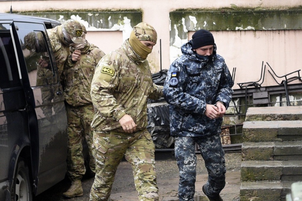 A Ukrainian sailor, right, is escorted by a Russian intelligence agency FSB officer to a courtroom in Simferopol, Crimea, on Tuesday. Photo: AP