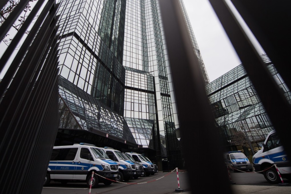 Police vans sit outside the headquarters of Deutsche Bank AG during a police raid. Photo: Bloomberg