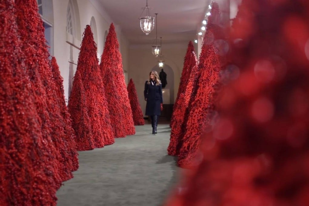 US first lady Melania Trump strolls through a forest of blood-red Christmas trees decorating a corridor of the White House. Photo: White House