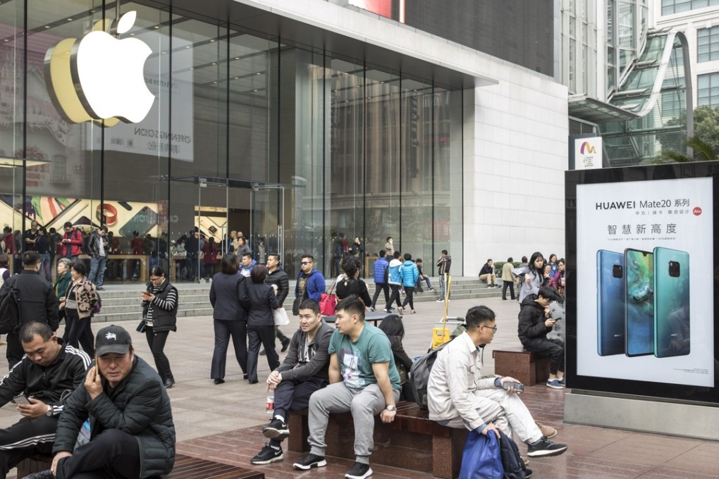 People sit on benches near an advertisement for the Mate 20 smartphone from Huawei Technologies outside an Apple Store in Shanghai. Photo: Bloomberg