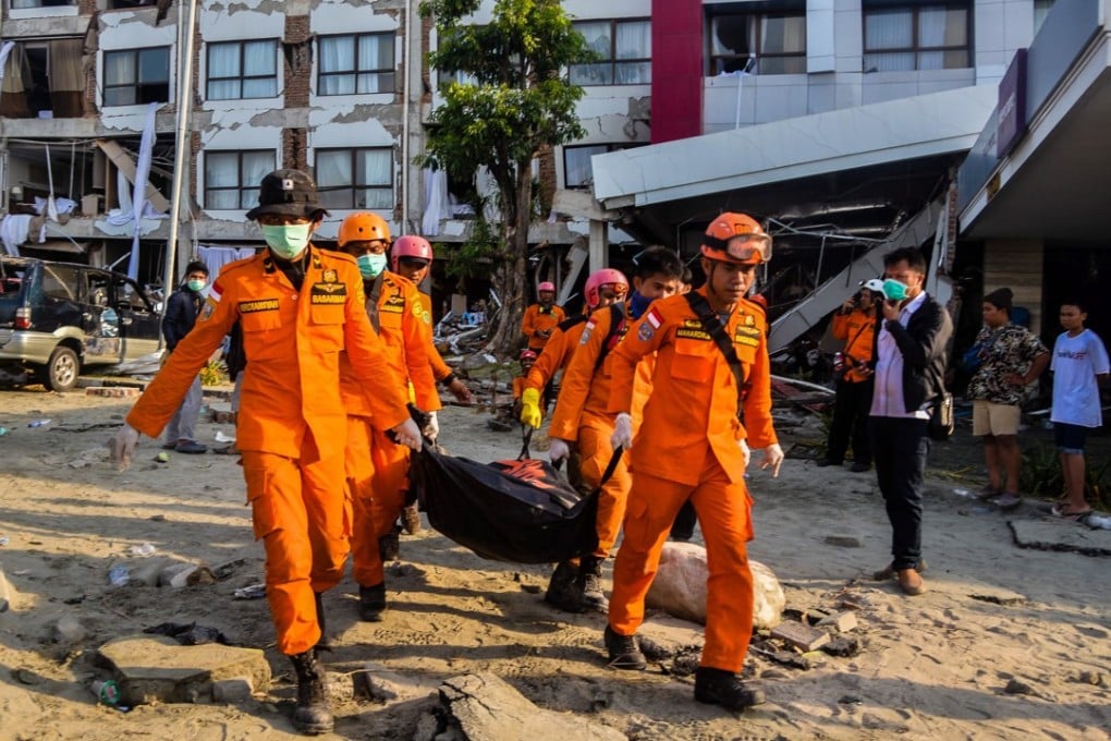 Rescuers carry the body of an earthquake victim from a damaged hotel building in Sulawesi. Photo: EPA