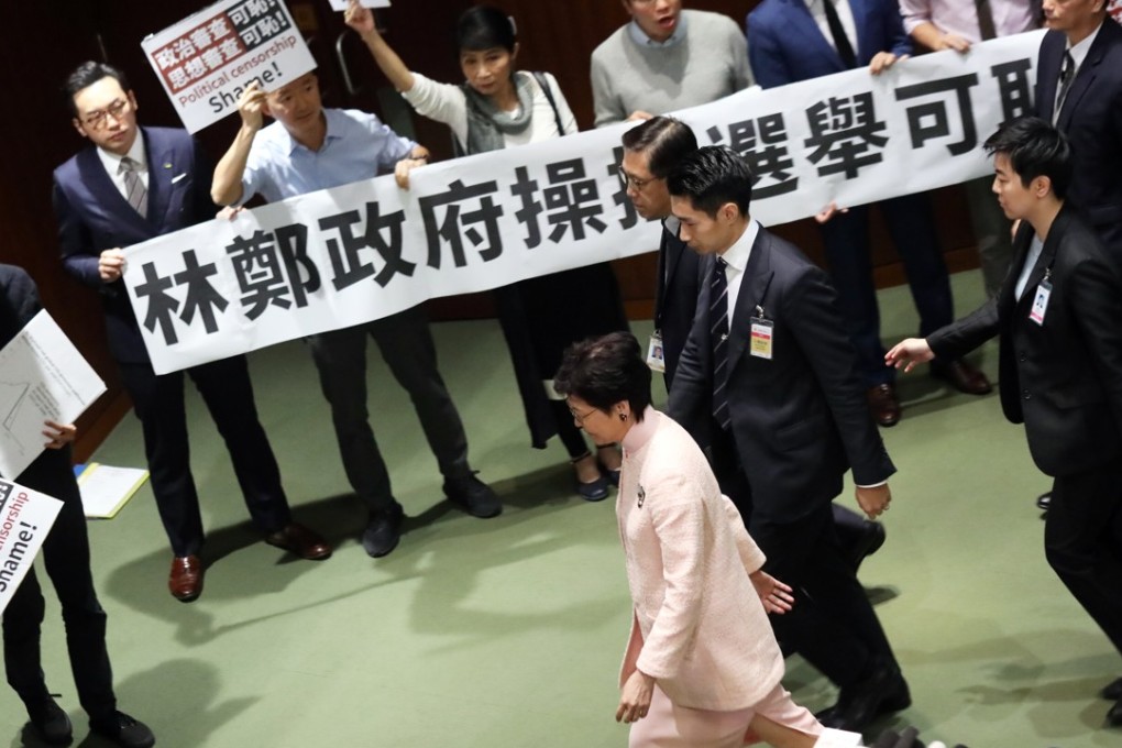 Ten pro-democracy lawmakers greet the chief executive outside the chamber with a banner proclaiming opposition to “government control of elections”. Photo: K.Y. Cheng