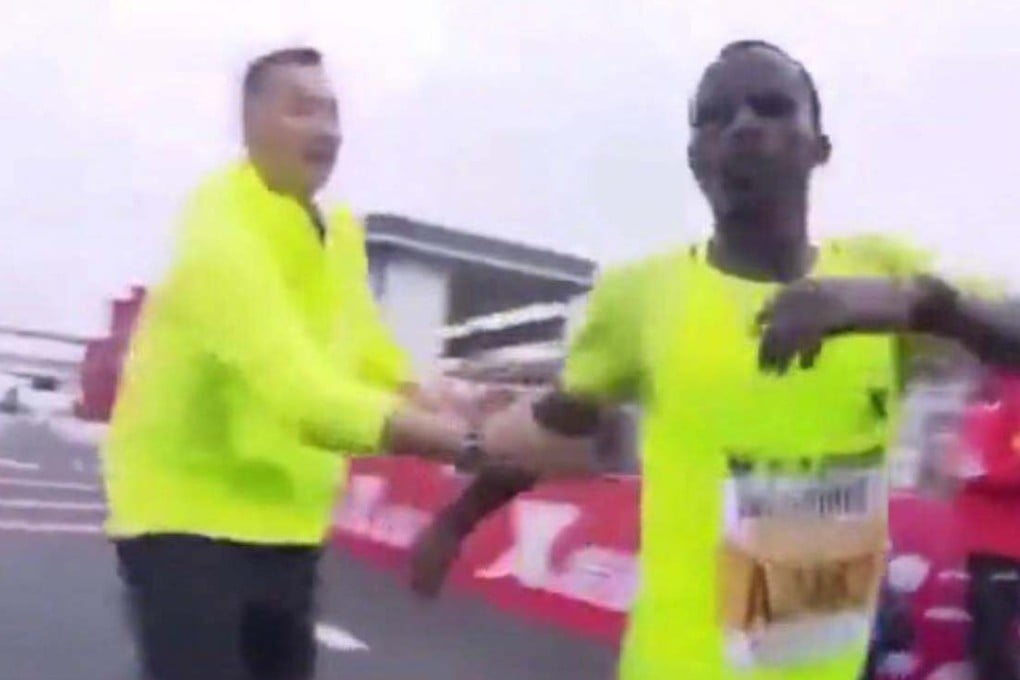 A marshal grabs Gelgelo Tona Outoya by the arm after he crosses the finish line at the Nanning marathon on Sunday. Photo: Weibo