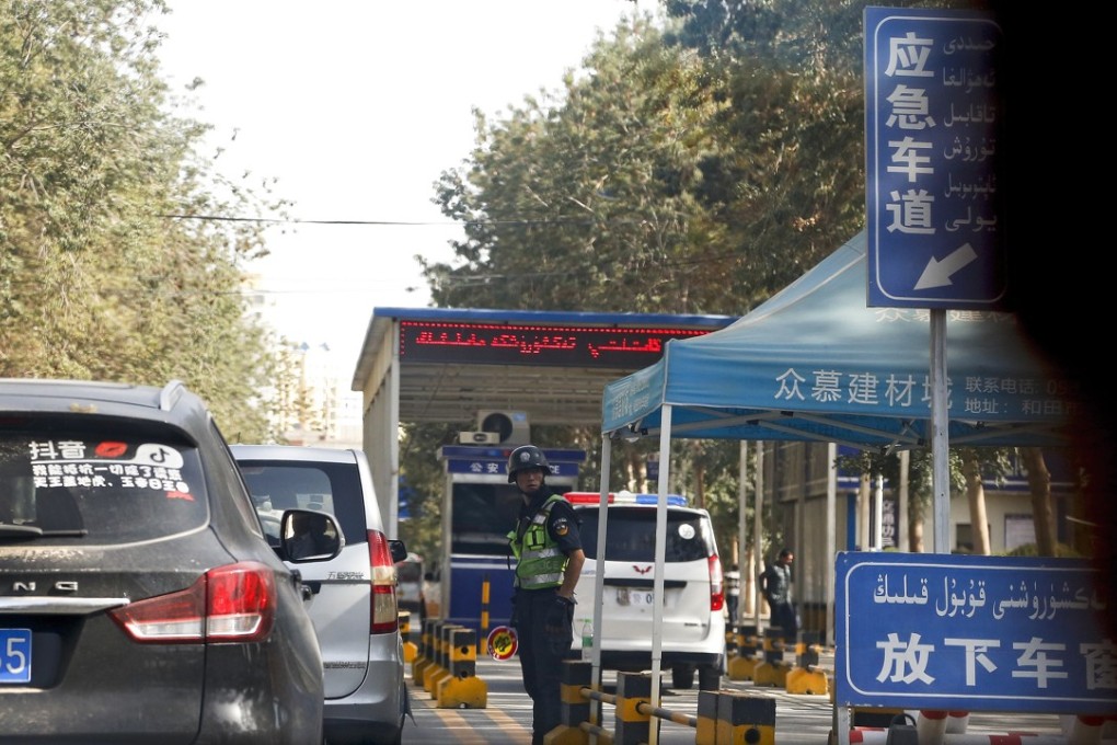 A policeman stands watch as vehicles drive past a checkpoint in Hotan, in western China's Xinjiang region. Photo: AP