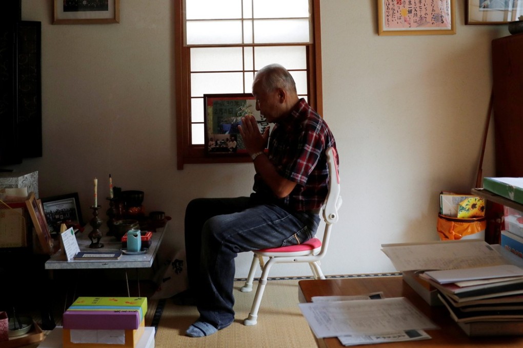 Katsuya Kodama prays in front of an altar for his late wife. Photo: Reuters