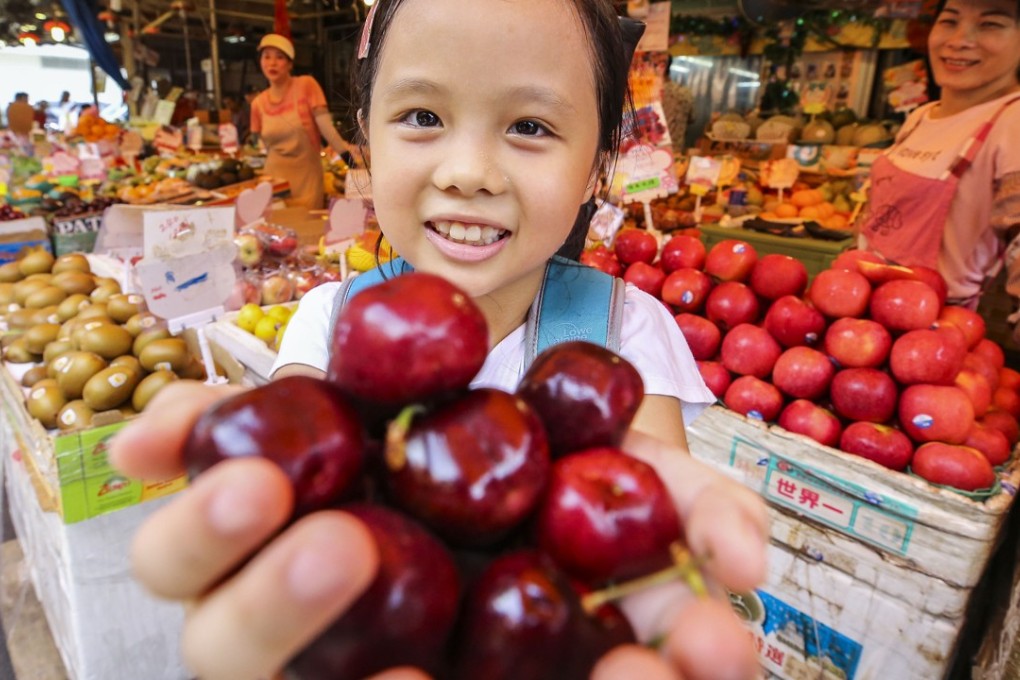 Schoolgirl Chloe Lam shops for cherries at the Yau Ma Tei fruit market. American-grown cherries have fallen in price in Hong Kong since tariffs were imposed on them on the mainland. Photo: Dickson Lee