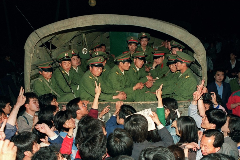 Pro-democracy demonstrators raise their fists and flash victory signs as they stop a military truck on its way to Tiananmen Square on May 20, 1989. Photo: AFP