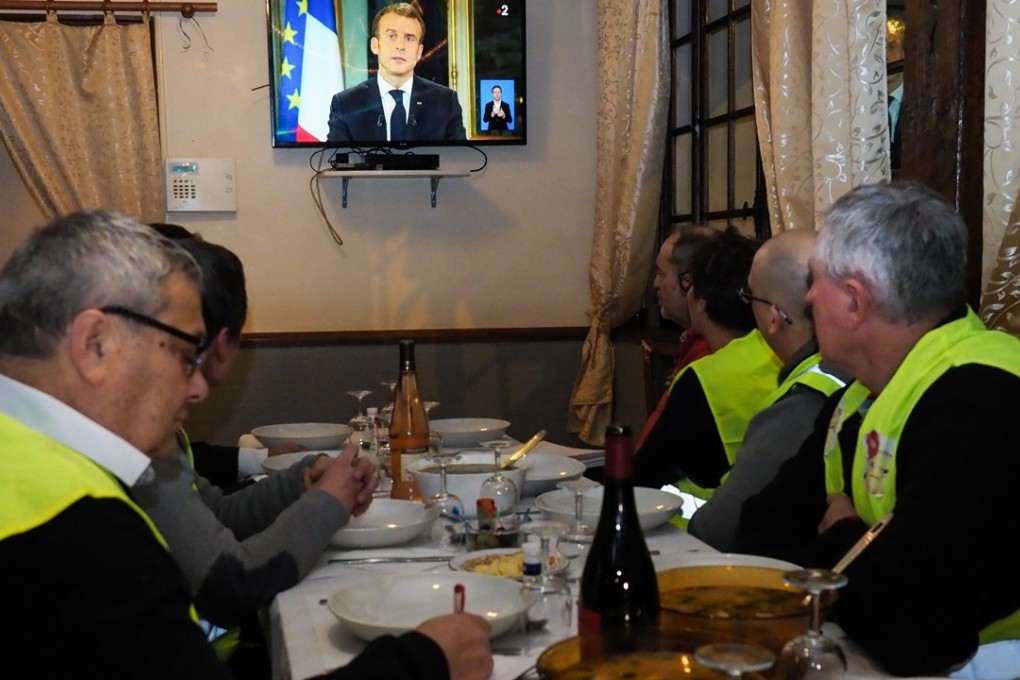 Yellow vest protesters take notes as they watch President Emmanuel Macron's speech on television on Monday. Photo: AFP