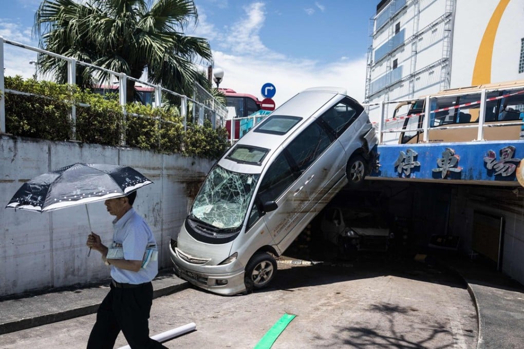 A man walking past a damaged car in the aftermath of Typhoon Hato in Macau on August 26, 2017. Photo: AFP