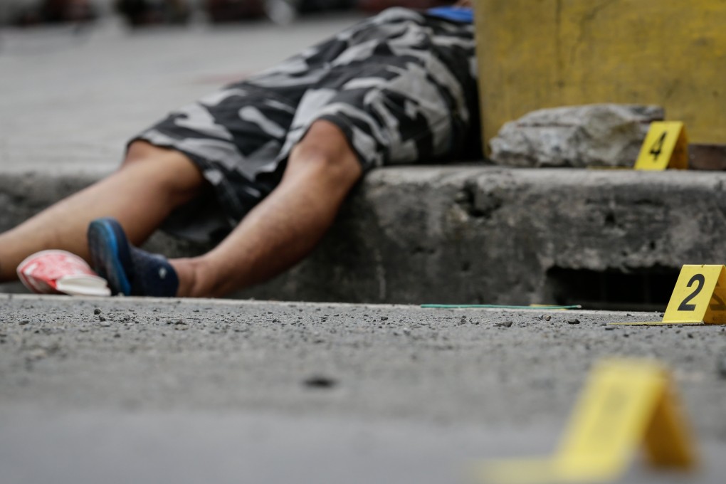 Evidence markers surround the body of a dead man shot in Makati, south of Manila. Photo: EPA