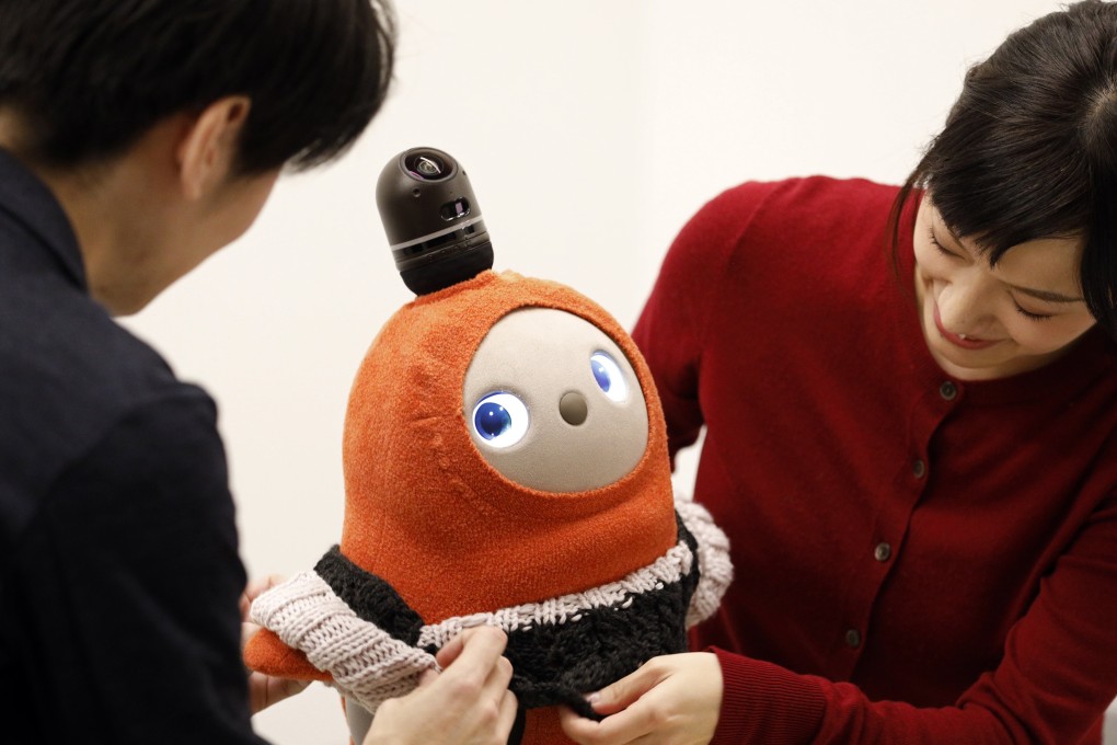 A man and a woman put clothing on Lovot. Photo: EPA