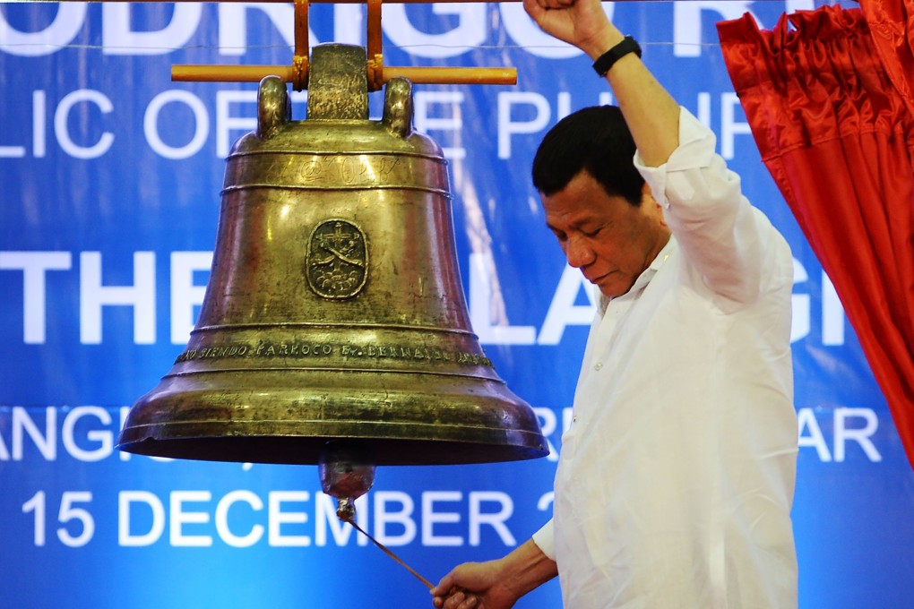 Raising a clenched fist, Philippine President Rodrigo Duterte rings one of the Balangiga church bells during a ceremony on December 15. Photo: AFP