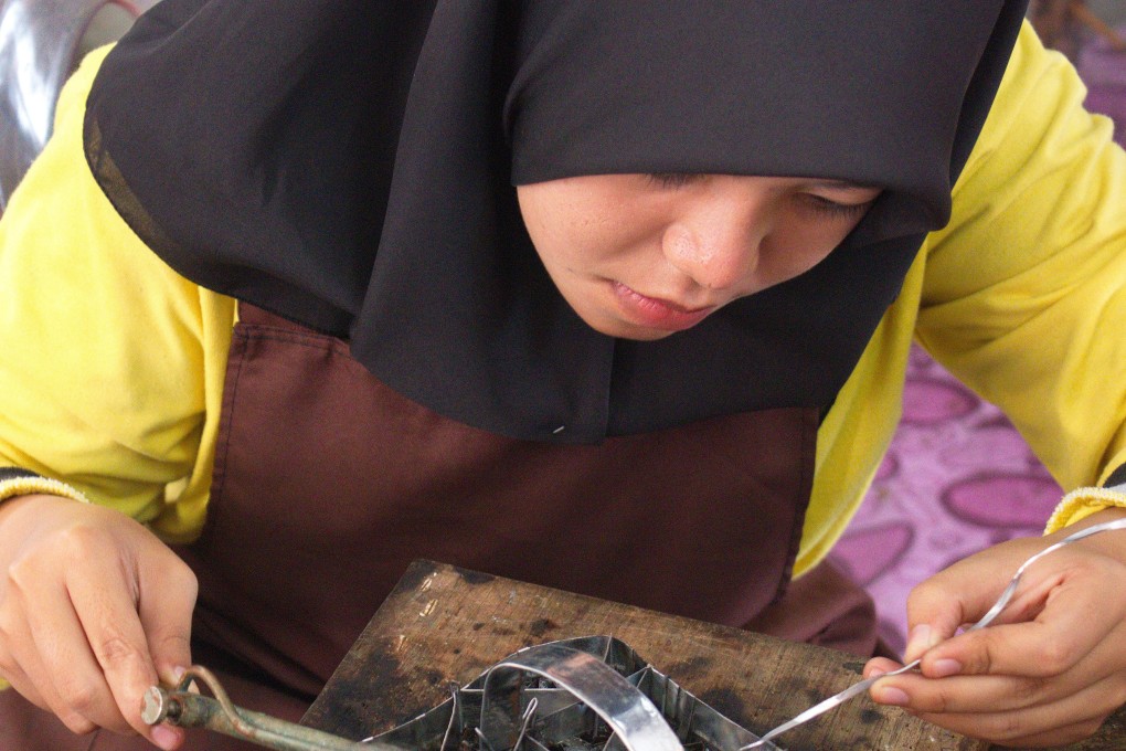 A woman solders a batik printing stamp in Kuala Terengganu, Malaysia. Photo: Keith Mundy
