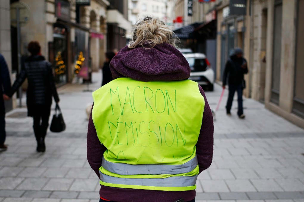 Ludivine Hilairet, a fast-food worker, poses for a photo back view and wearing a “Yellow Vest” (Gilet Jaune) reading “Macron resignation” in a street of Caen, northwestern France. Photo: AFP