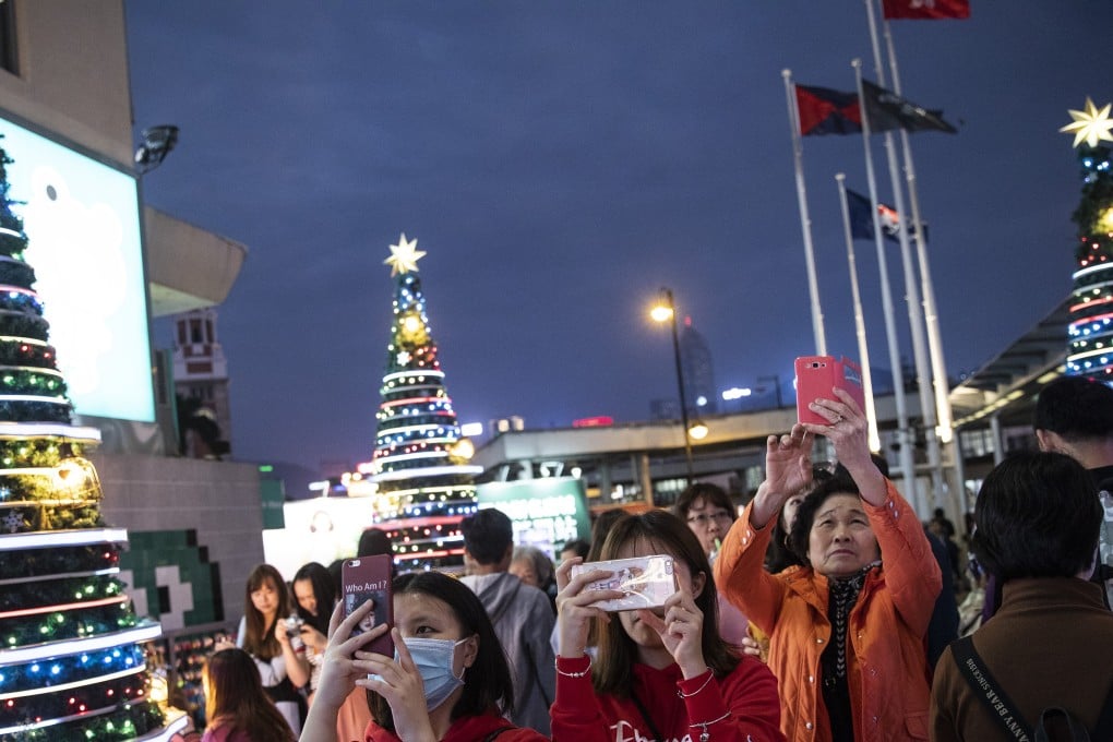 Visitors take photos of illuminated Christmas trees outside a harbourfront shopping mall in Tsim Sha Tsui, Hong Kong. Photo: Bloomberg