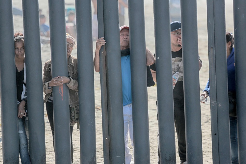 Would-be migrants to the United States from Honduras peer through the fence demarcating the US-Mexico border in San Ysidro, California on November 18. Photo: AFP