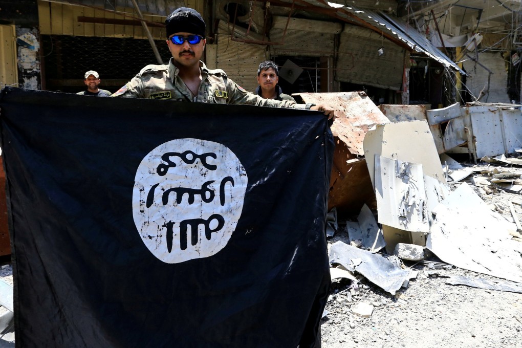 A member of the emergency response division holds an Islamic State militants flag in the Old City of Mosul in July 2017. Photo: Reuters